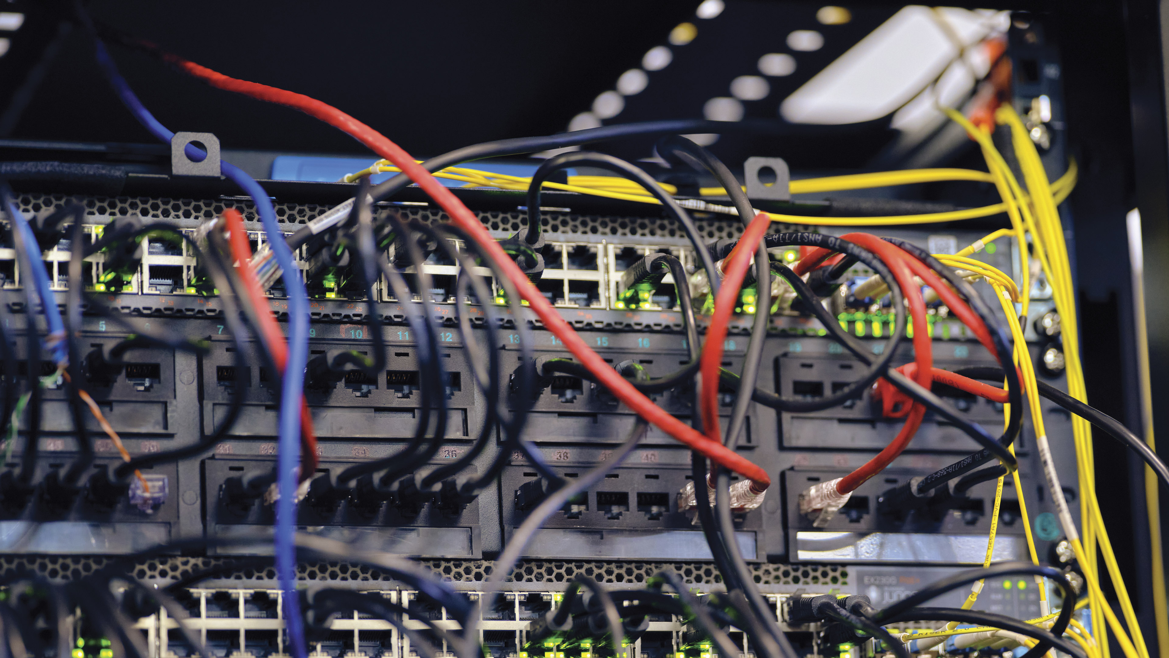 Close view of network equipment with multiple colored cables connected to ports inside a data or telecommunications cabinet