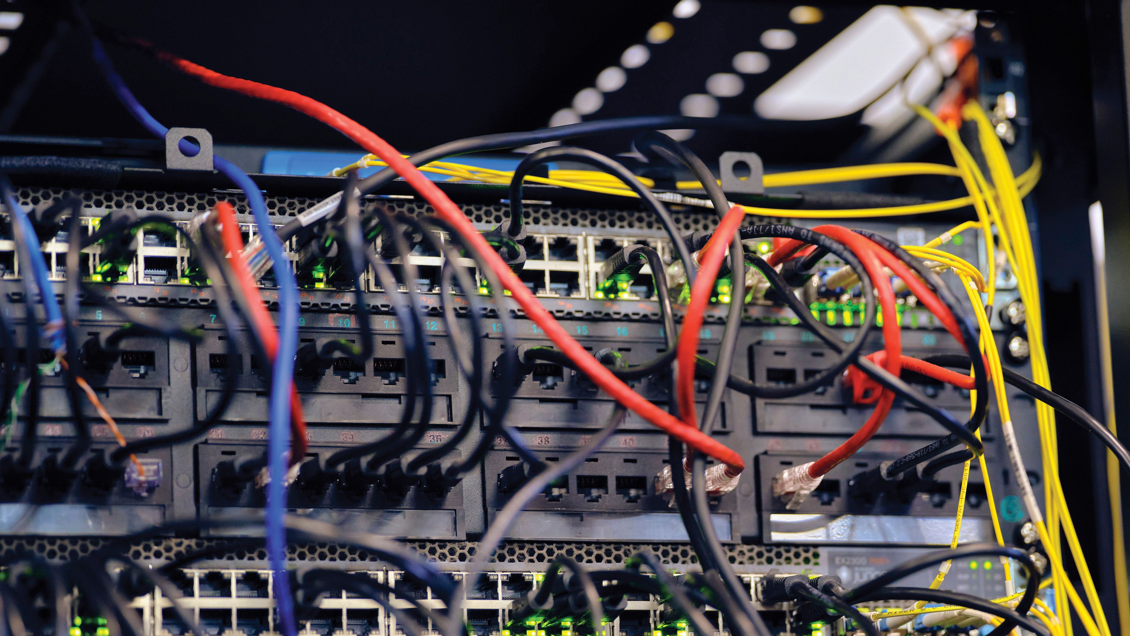 Close view of network equipment with multiple colored cables connected to ports inside a data or telecommunications cabinet