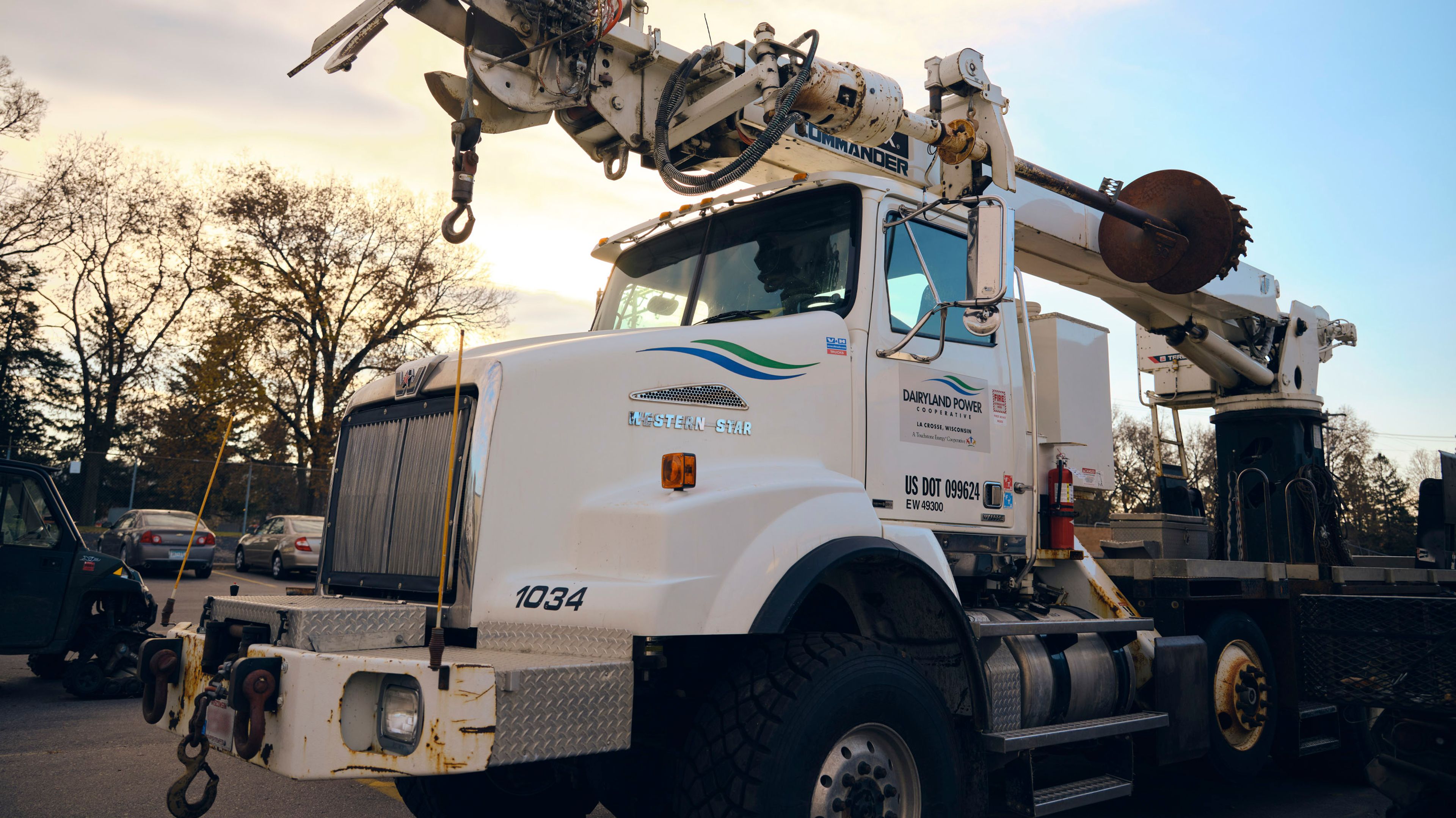 Utility service truck with a mounted boom parked near overhead power lines