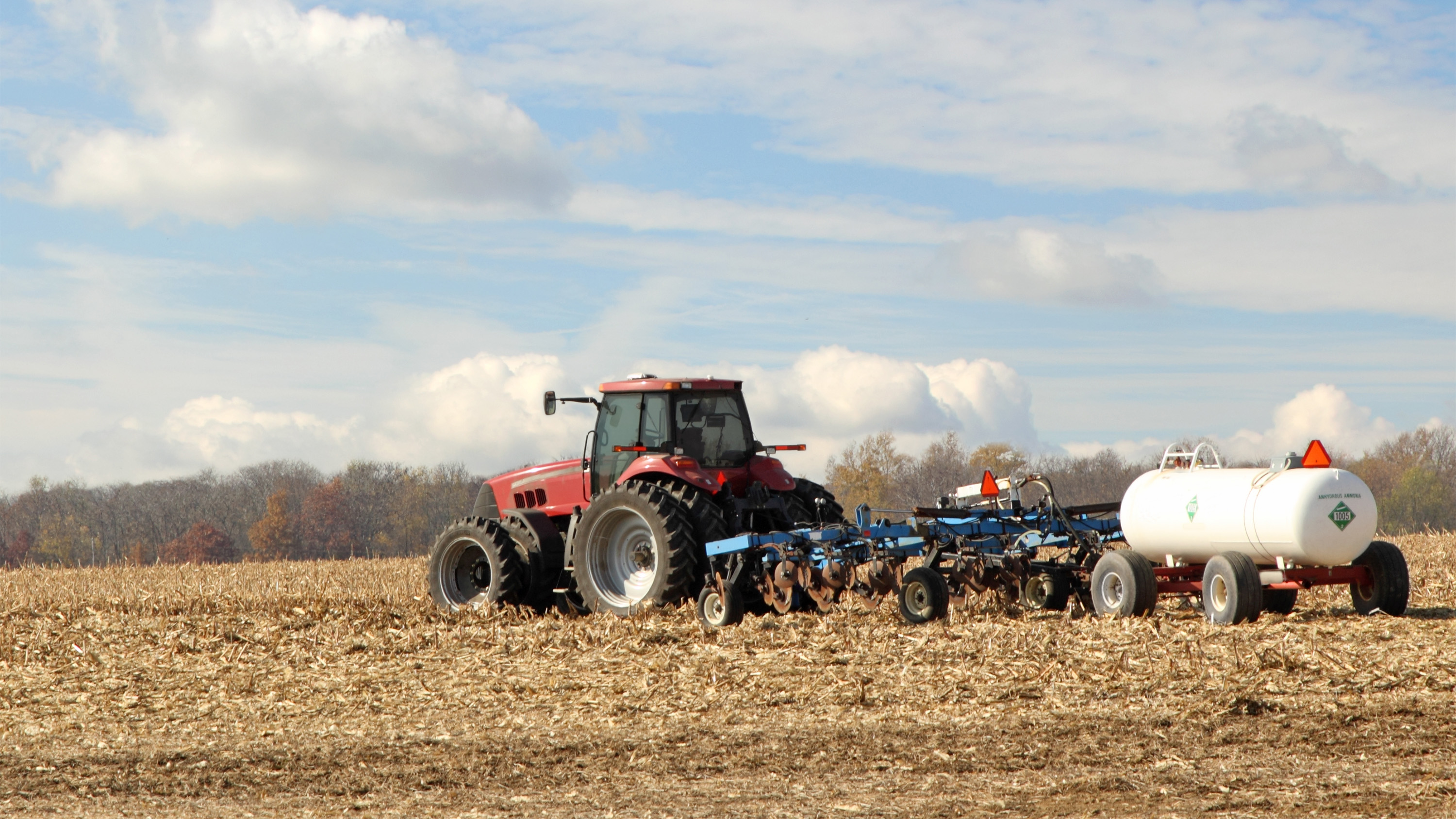 Tractor pulling ammonia fertilizer tank through field
