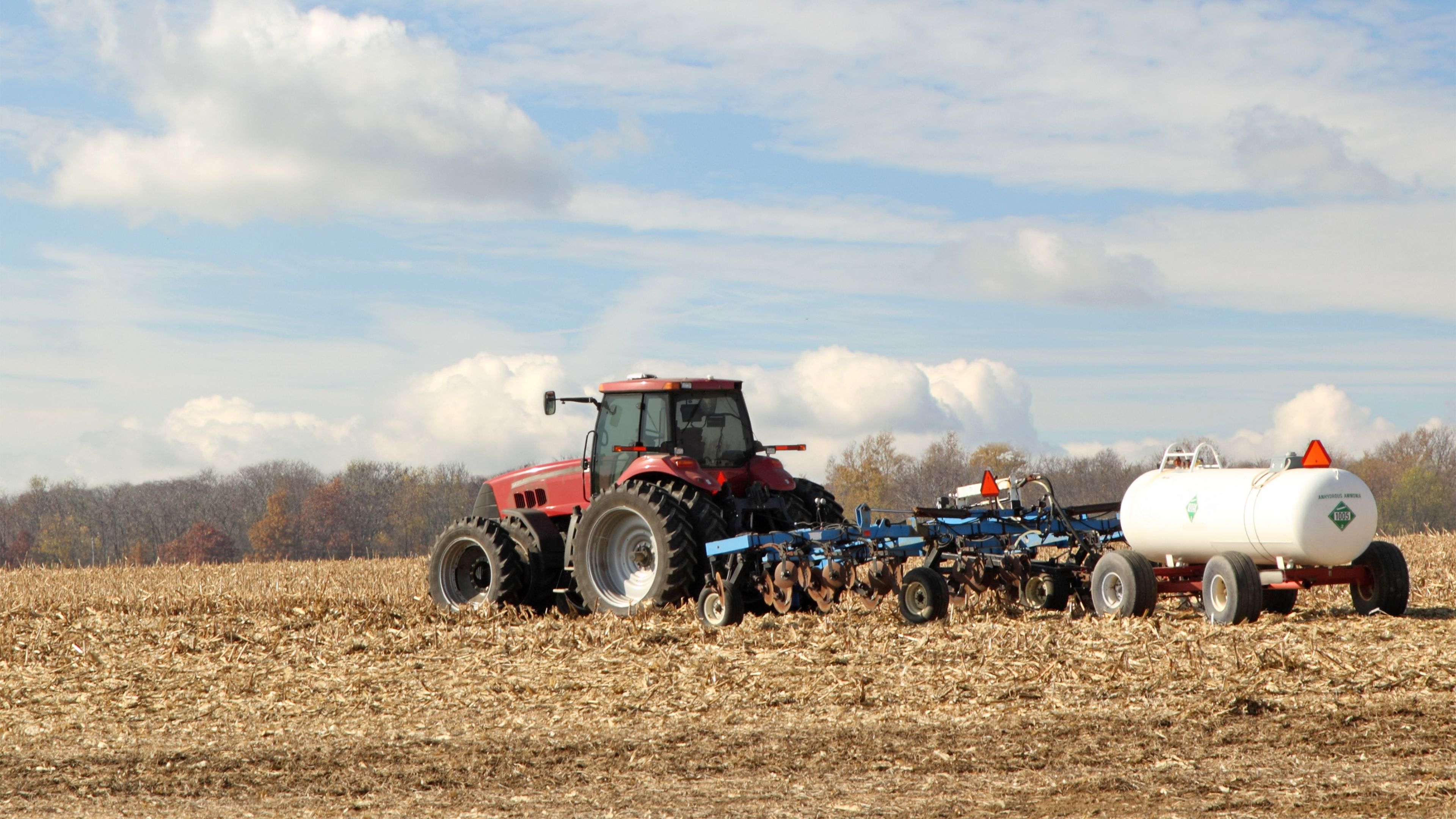 Tractor pulling ammonia fertilizer tank through field