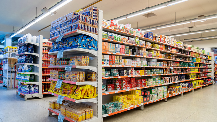 Grocery store aisle with shelves of packaged food products under bright lighting