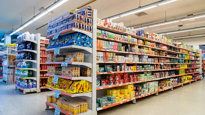 Grocery store aisle with shelves of packaged food products under bright lighting