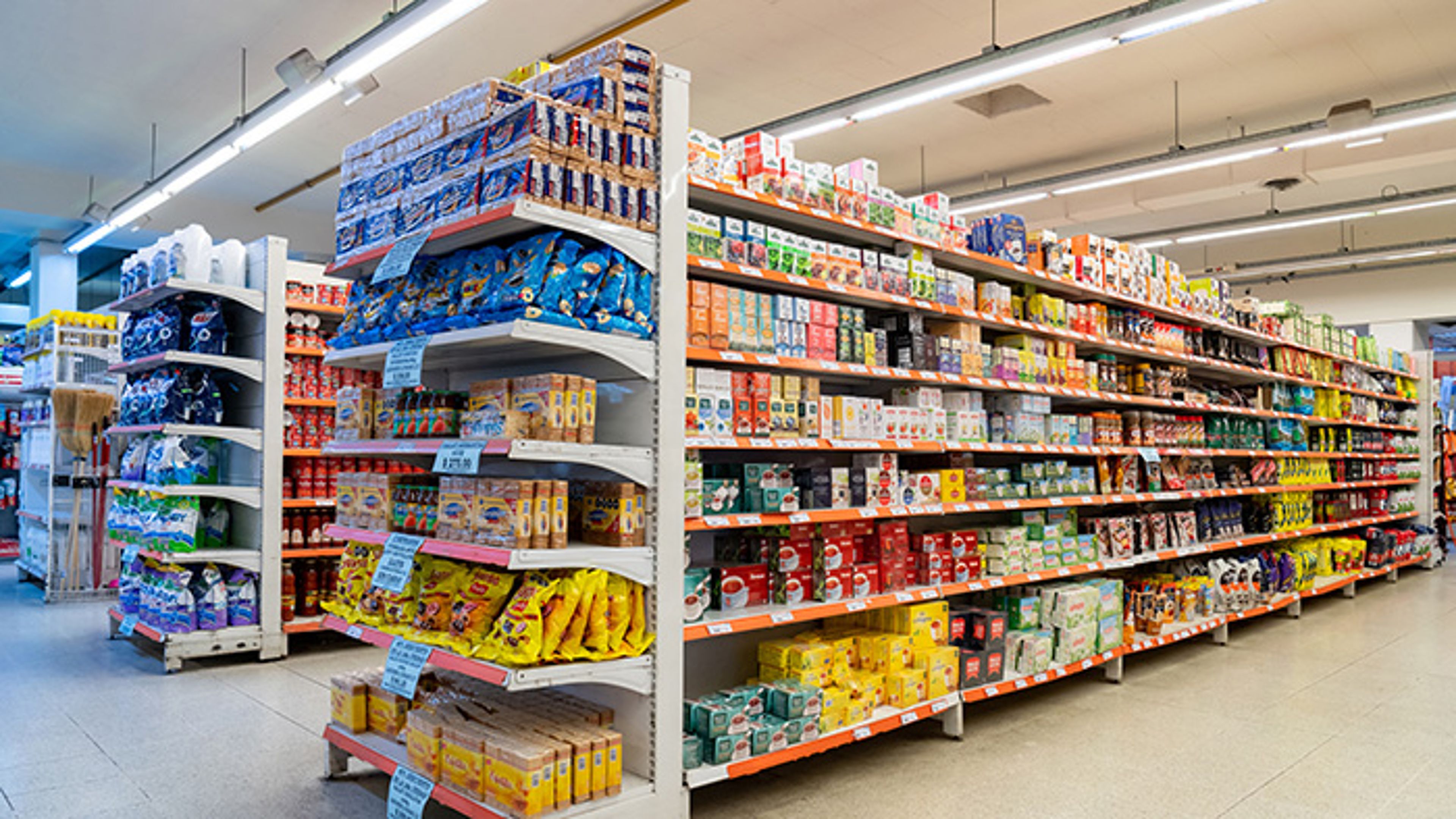 Grocery store aisle with shelves of packaged food products under bright lighting