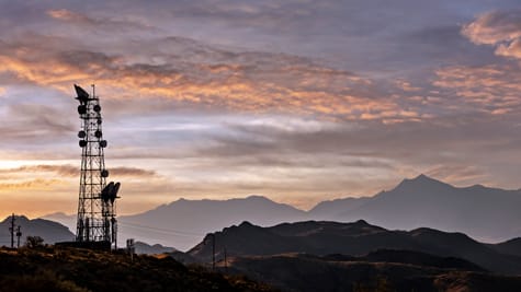 Communications tower on a hill silhouetted before a moody sky