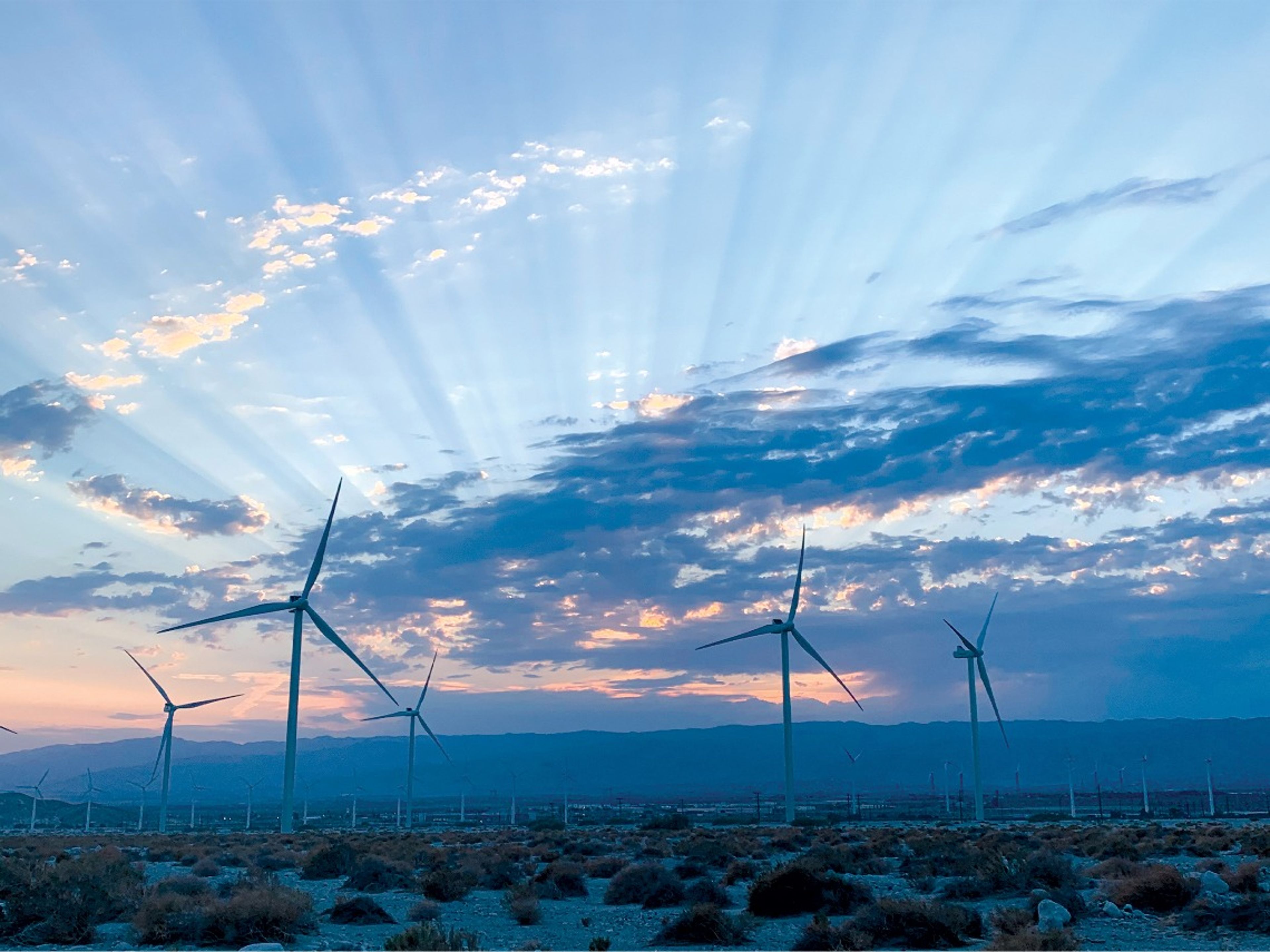 Wind turbine field in desert area with cloudy sky
