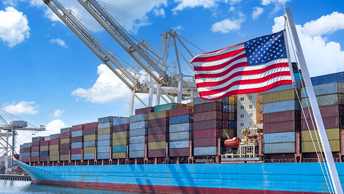 Shipping containers on a freight ship, United States flag waving in the foreground