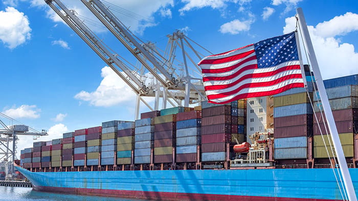 Shipping containers on a freight ship, United States flag waving in the foreground