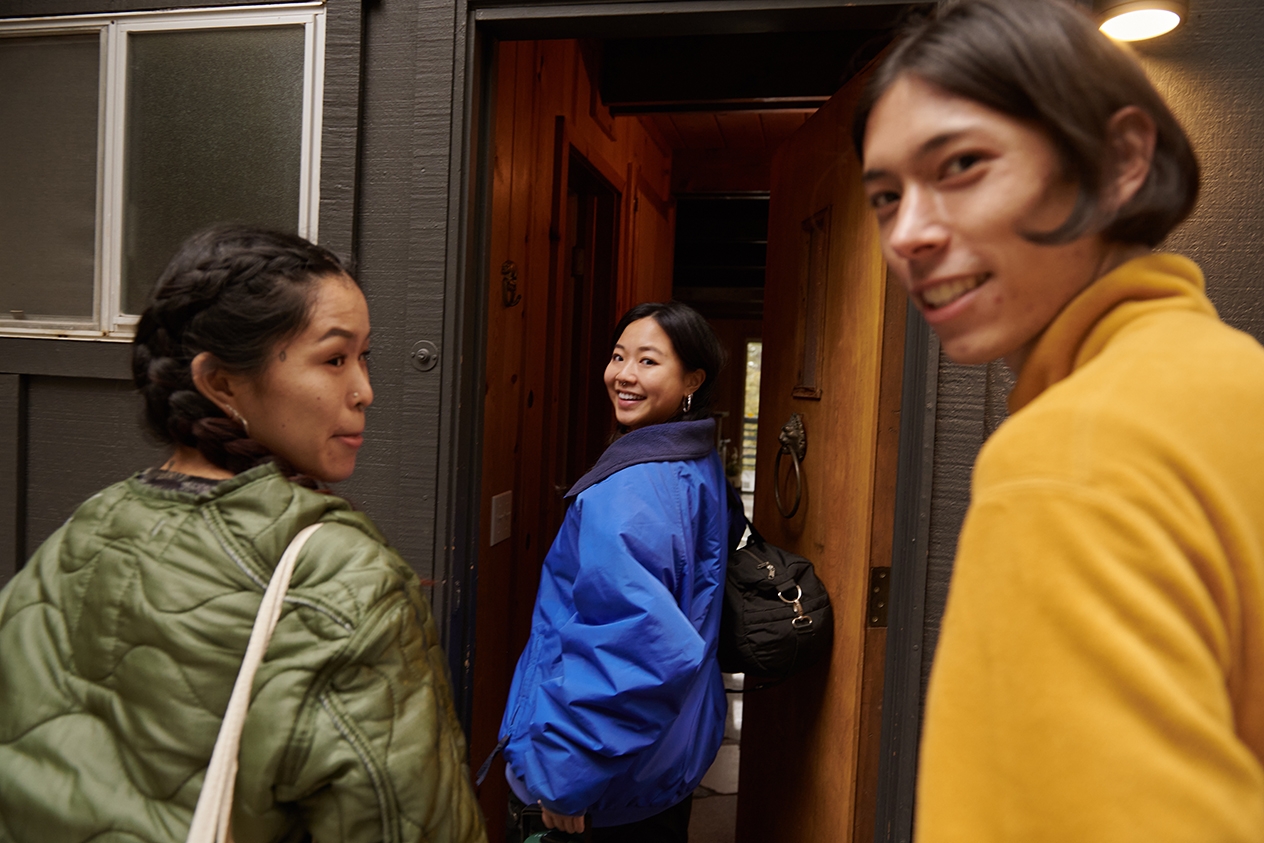 Tres personas entran en un alojamiento que han reservado a través de Airbnb por la puerta principal.