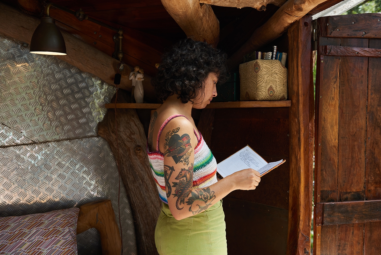 Una mujer está de pie junto a una balda, leyendo una guía.