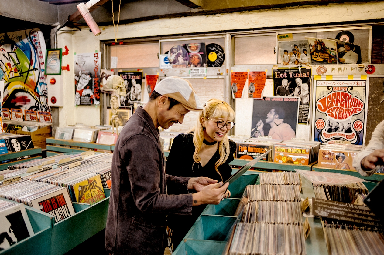 Du žmonės naršo muzikos įrašų parduotuvėje.