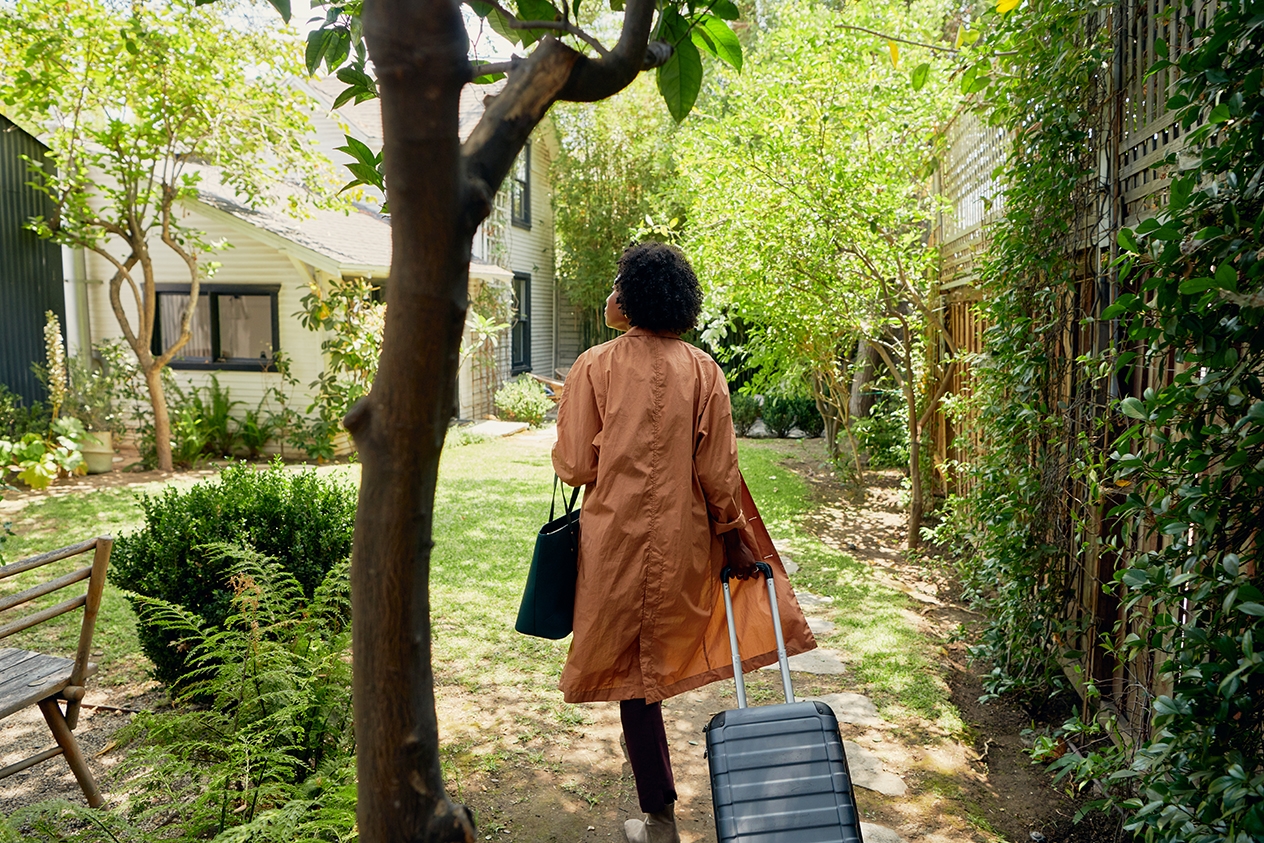 A person arrives at their Airbnb stay, bringing a suitcase.