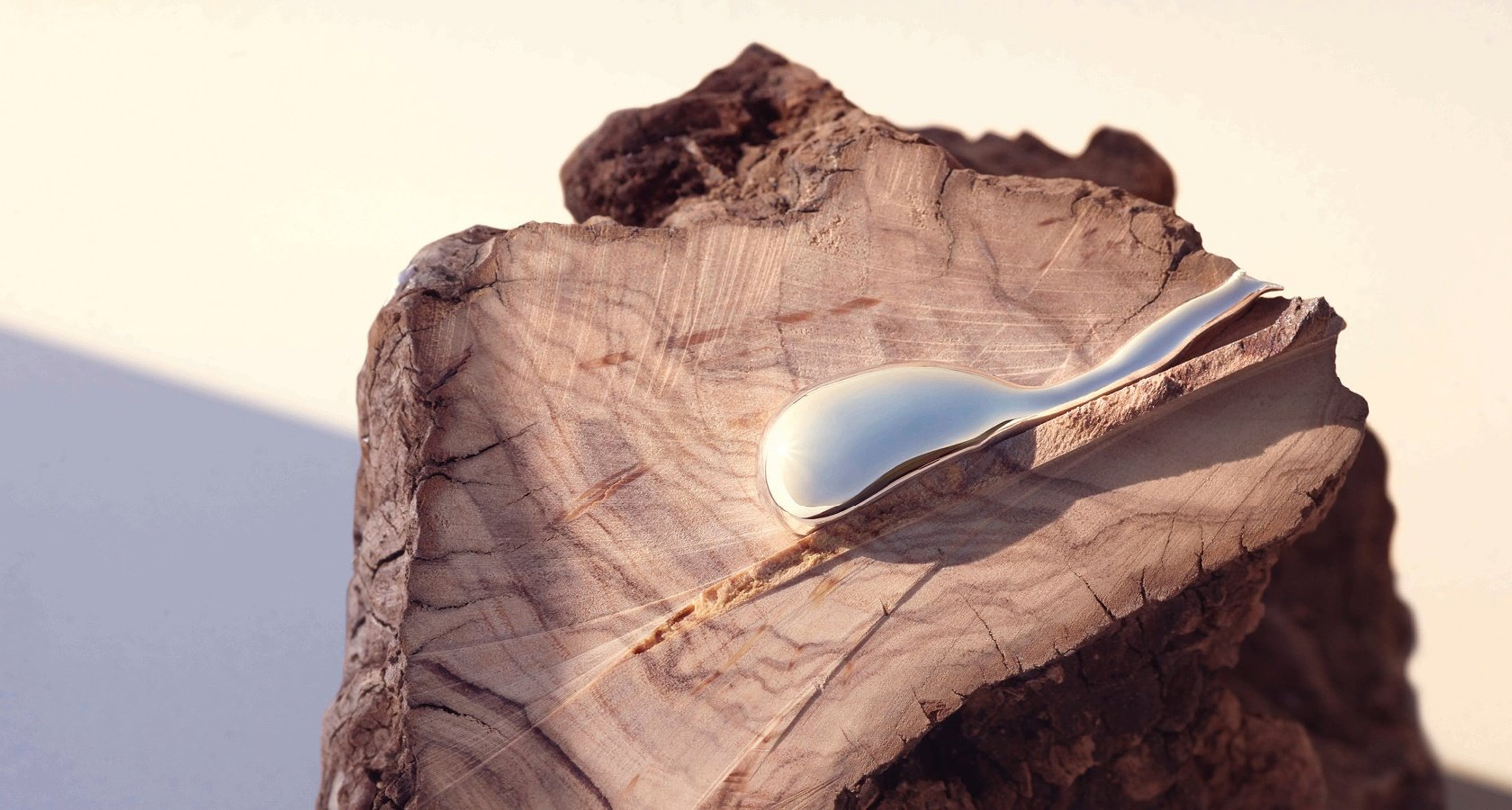 Silver liquid flows down the textured wooden surface with natural light