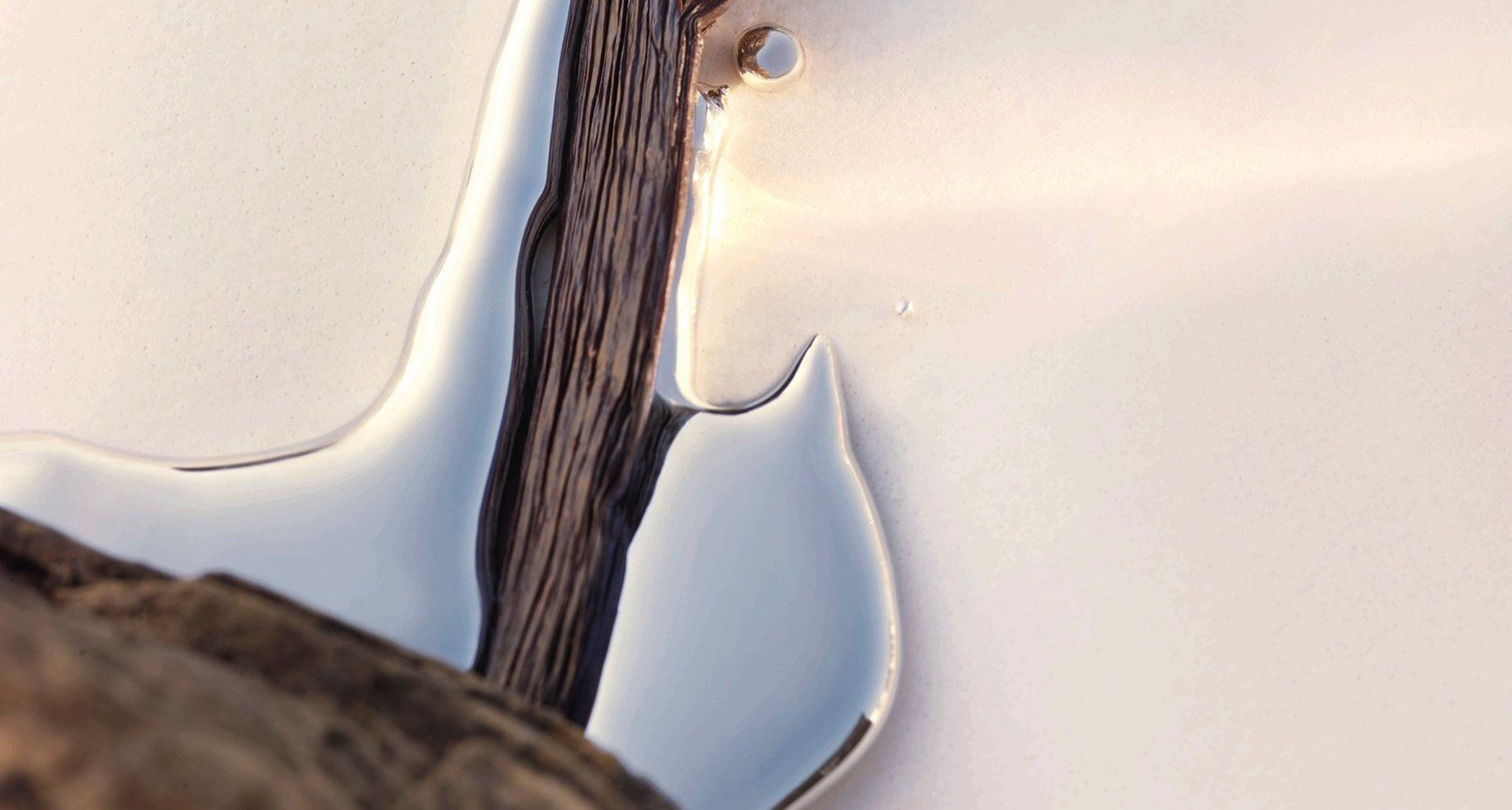 Close-up of a water droplet on a smooth surface with a light reflection