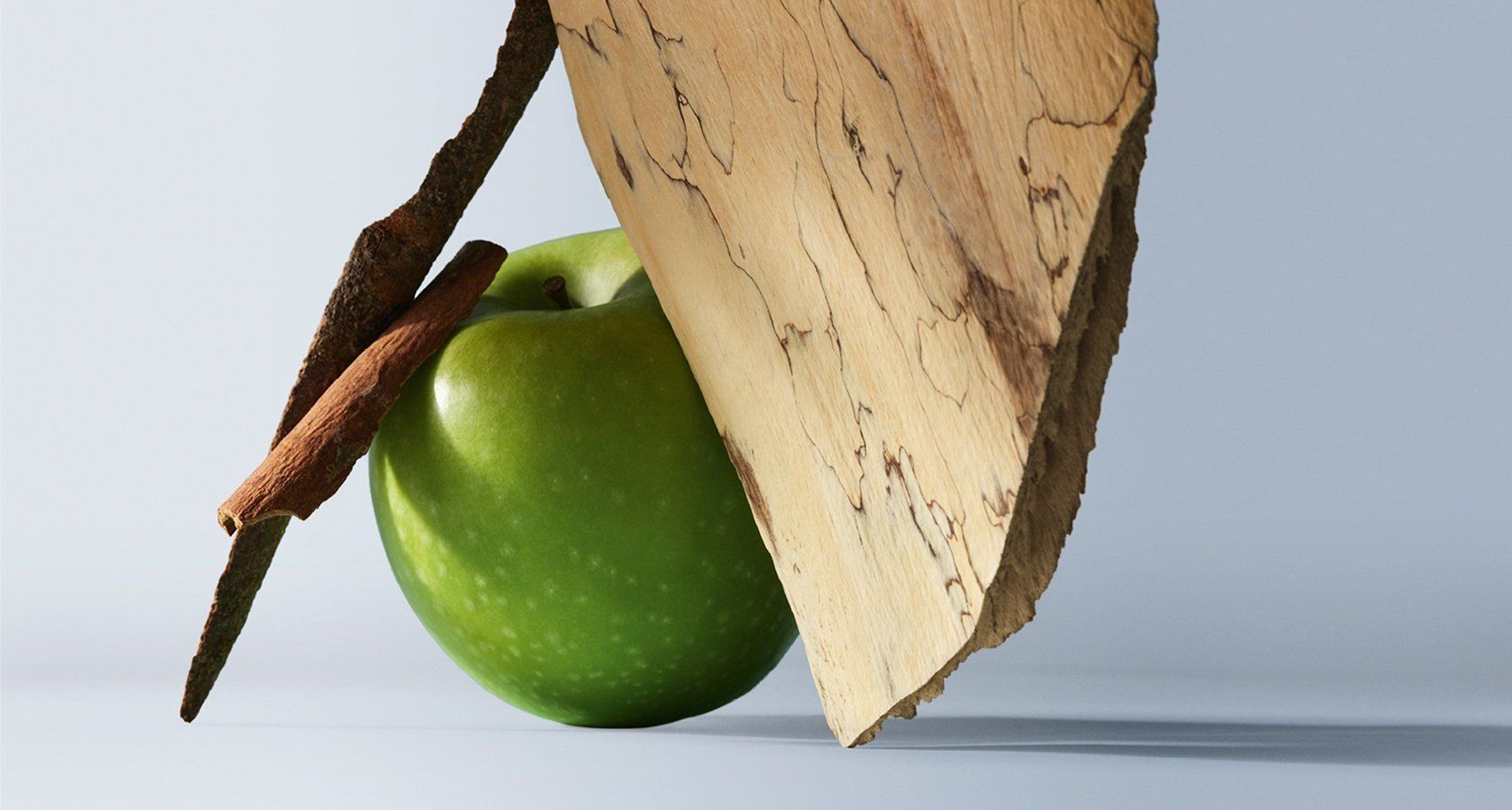 Green apple with a cinnamon stick and wedge of aged cheese on a light background