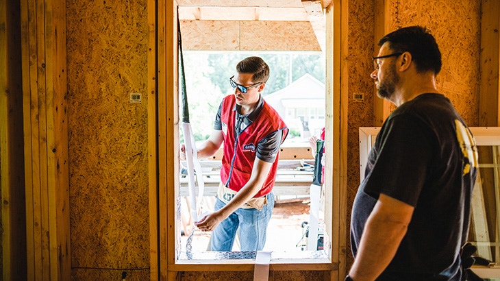 A Pella team member and a Lowe's team member are working on a home together