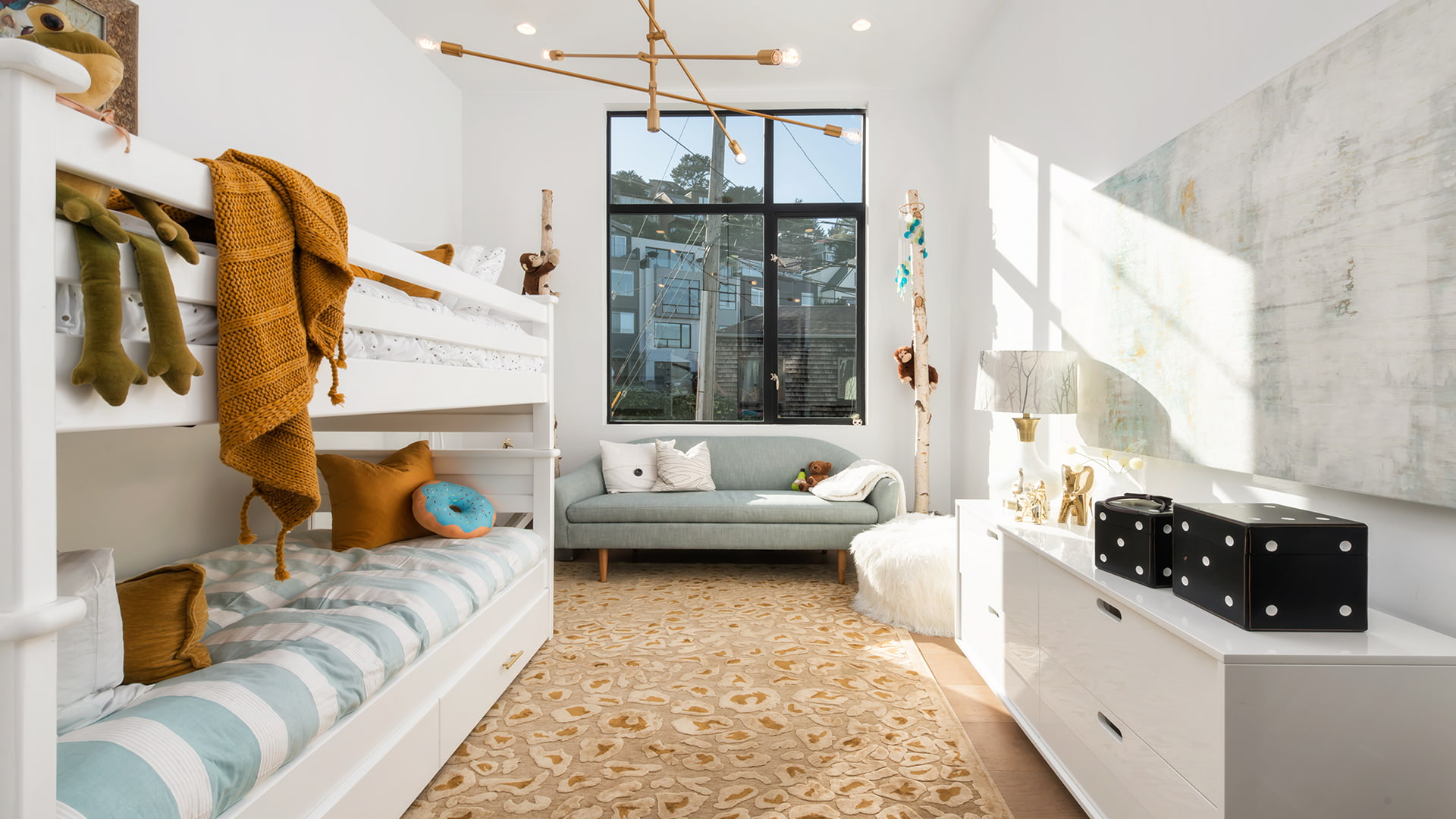 A child's bedroom with modern light fixtures, modern art, and orange-accent decor