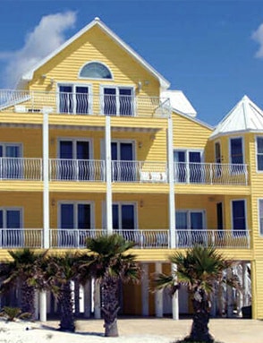 a yellow beach-front home with aluminum windows and doors