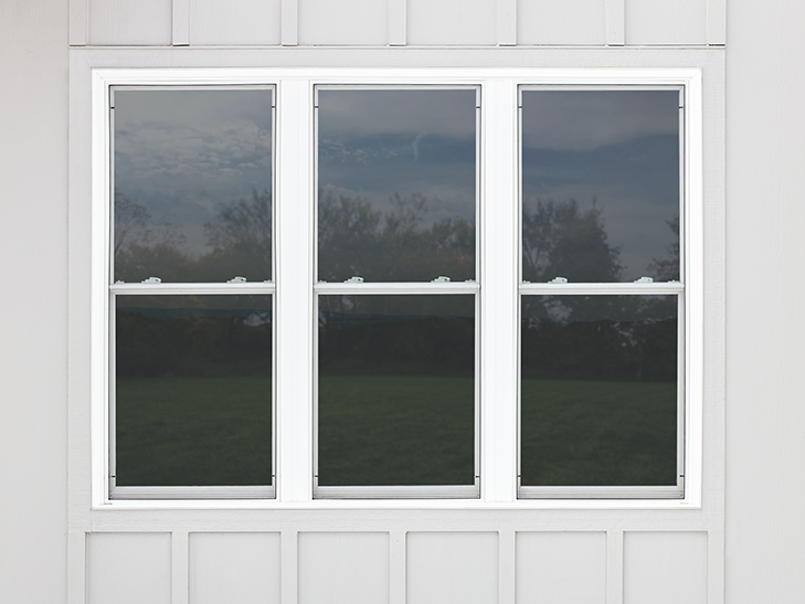 three single-hung vinyl windows viewed from the exterior of a gray-sided home