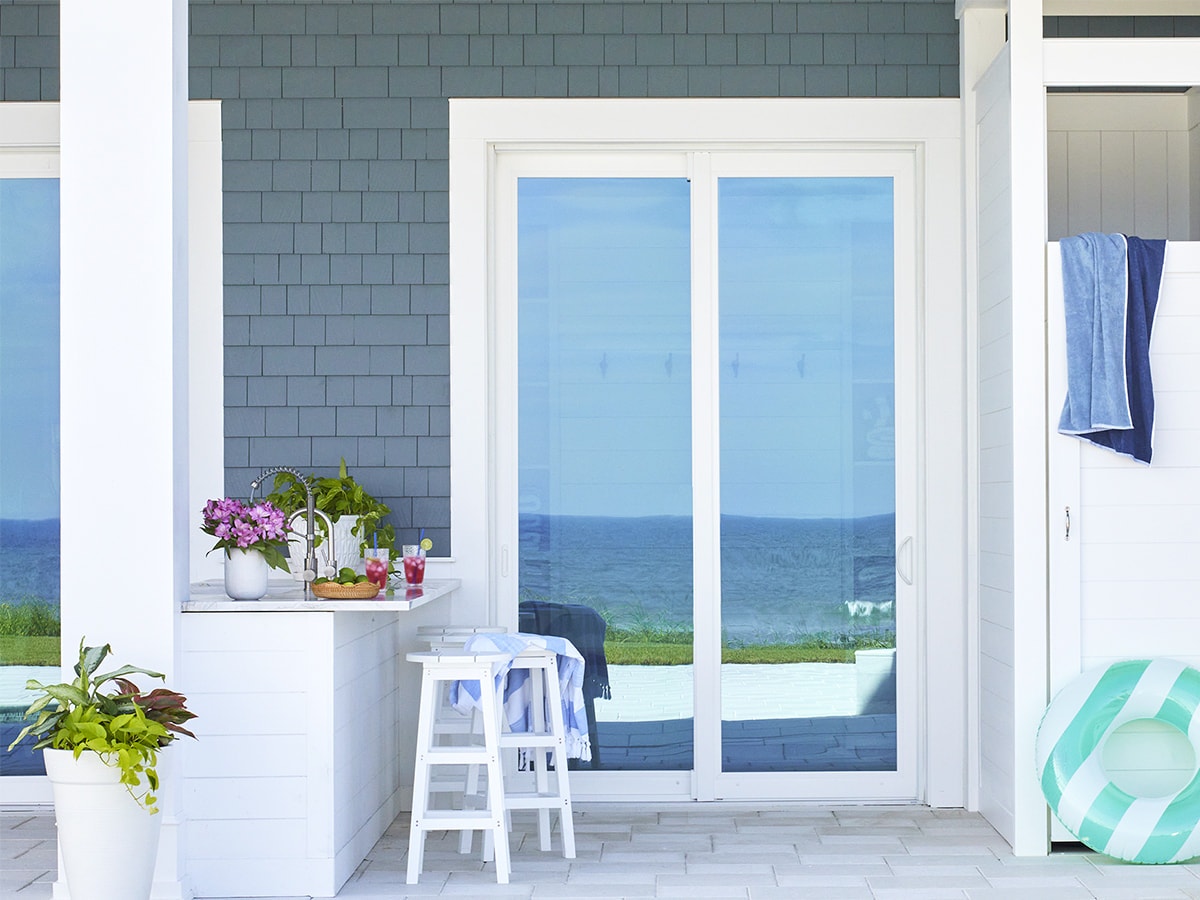 A two-panel white sliding patio door reflecting the ocean in the glass