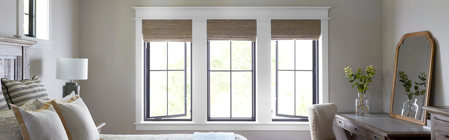 Three black casement windows with wicker shades