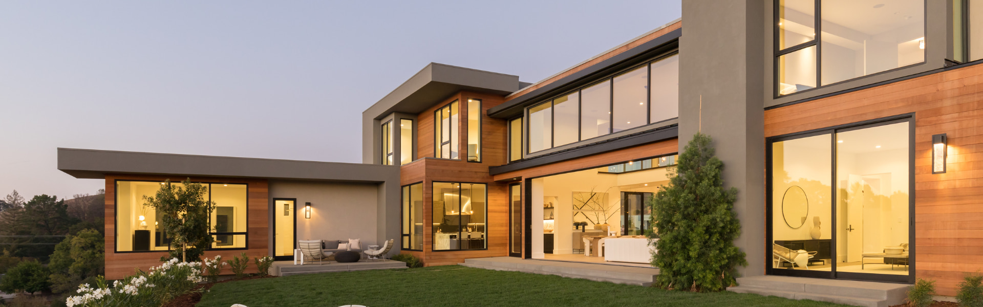 the exterior of a contemporary home with floor-to-ceiling windows and exterior lighting
