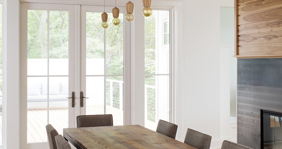 white hinged door at the end of a long wood dining room table