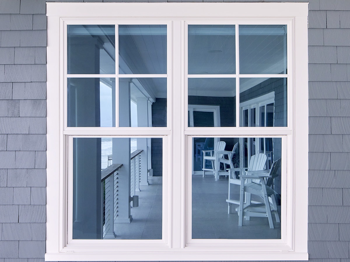 two white single-hung windows on a blue home with wood siding
