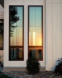 two tall casement windows reflect the sunset