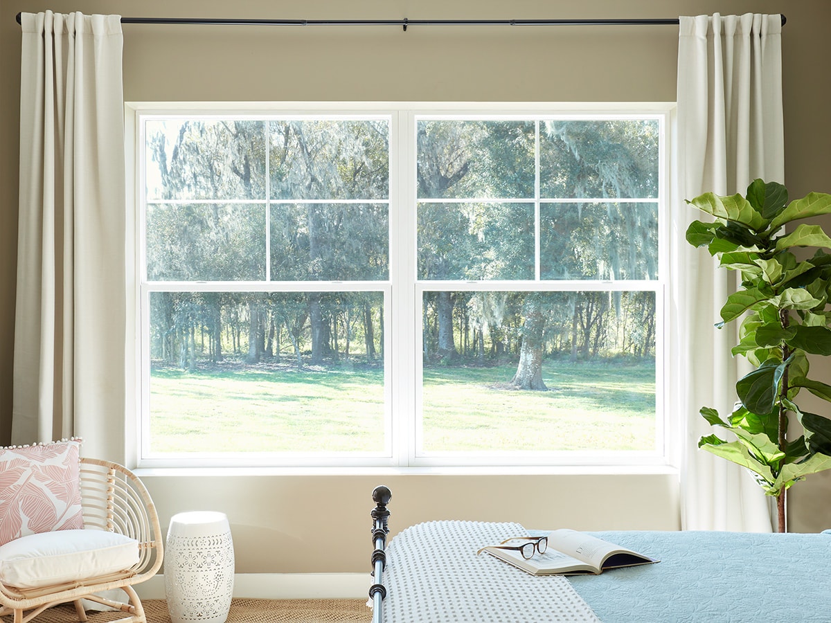 Two single-hung windows on a tan wall in a master bedroom.
