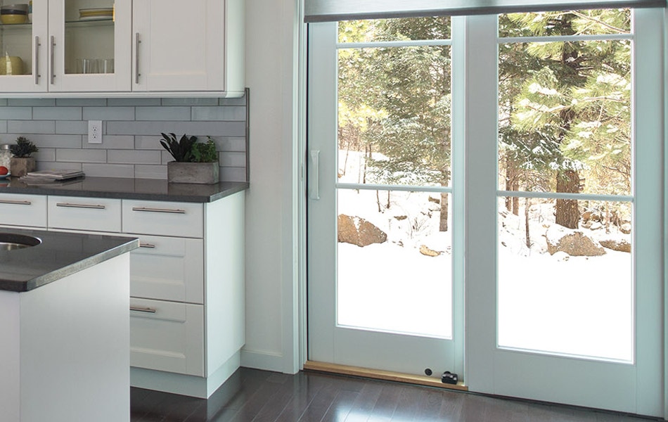 a winter scene outside a warm kitchen with a white sliding patio door
