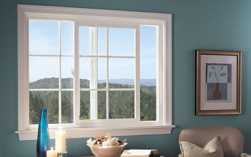 A white sliding window with grilles is partially open