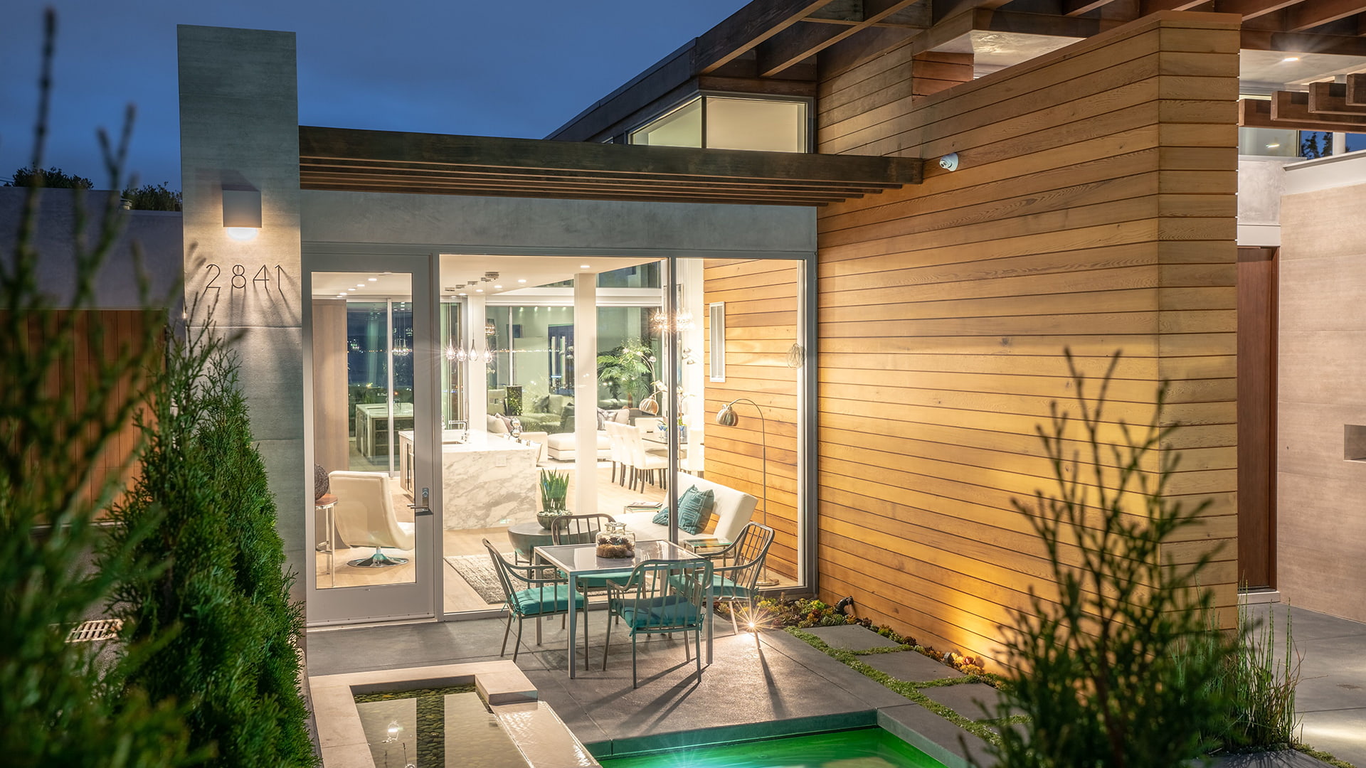 A window wall separates a patio table from a contemporary dining room