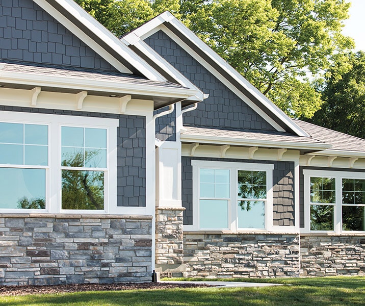 the exterior of a home with blue wood siding and brick accents.