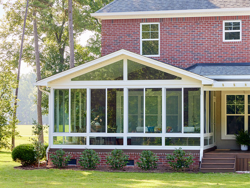 brick home with a large sunroom at the back