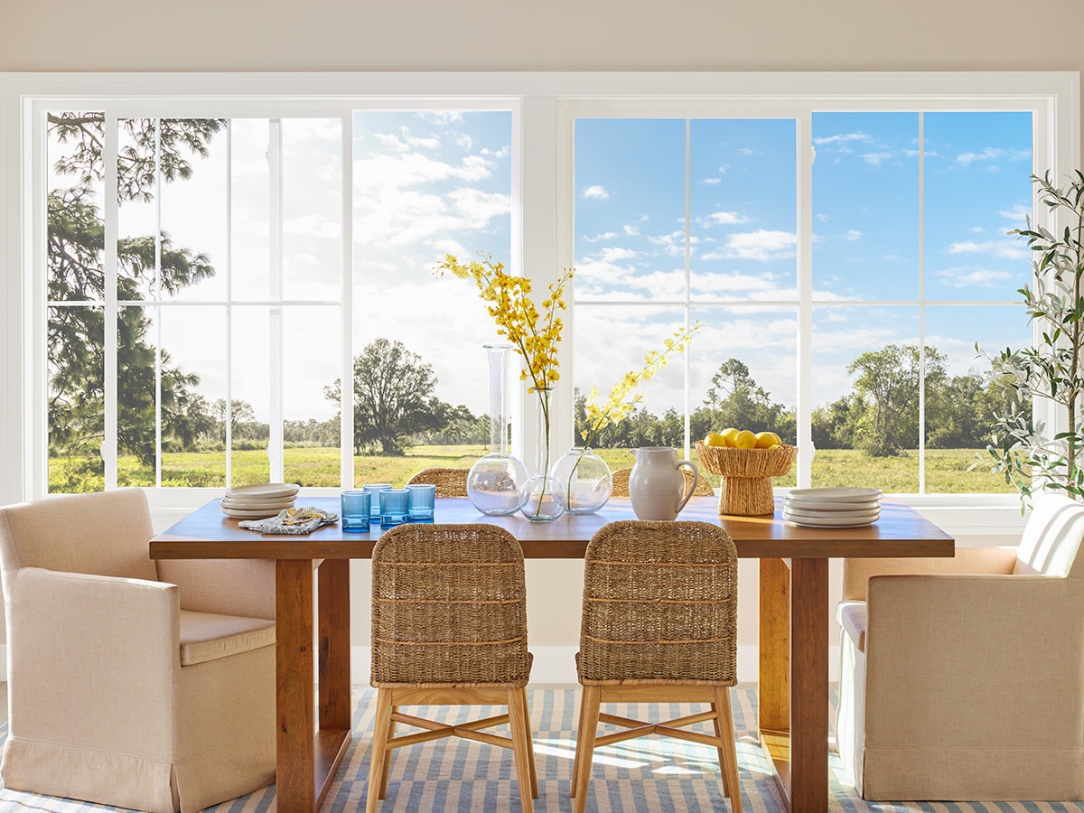 coastal dining room table in front of two sliding windows
