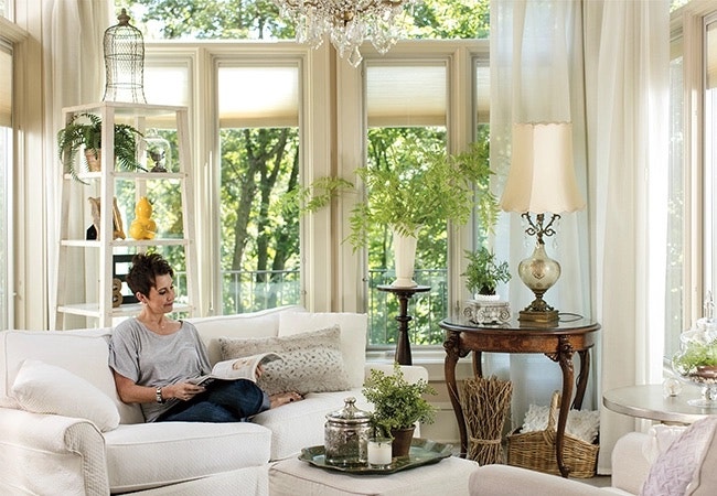 a woman is relaxing on a couch in front of floor-to-ceiling windows