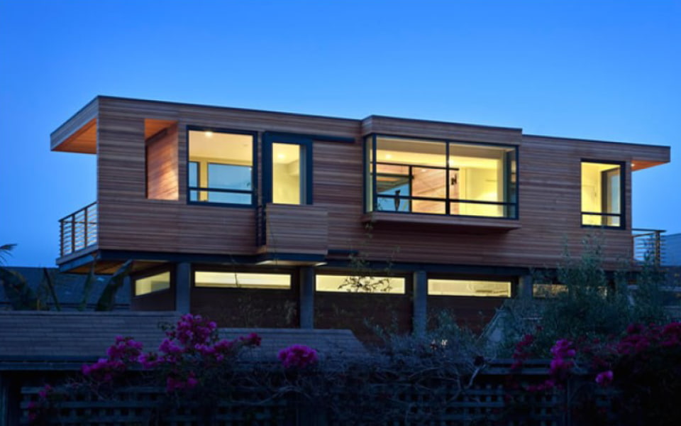 The back exterior of a unique-styled home with wood cladding as siding