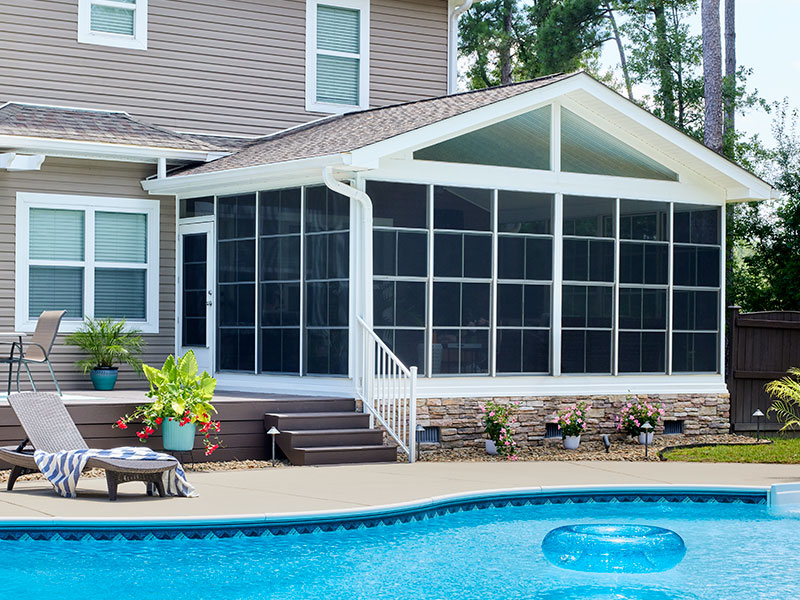 a swimming pool in front of a sunroom