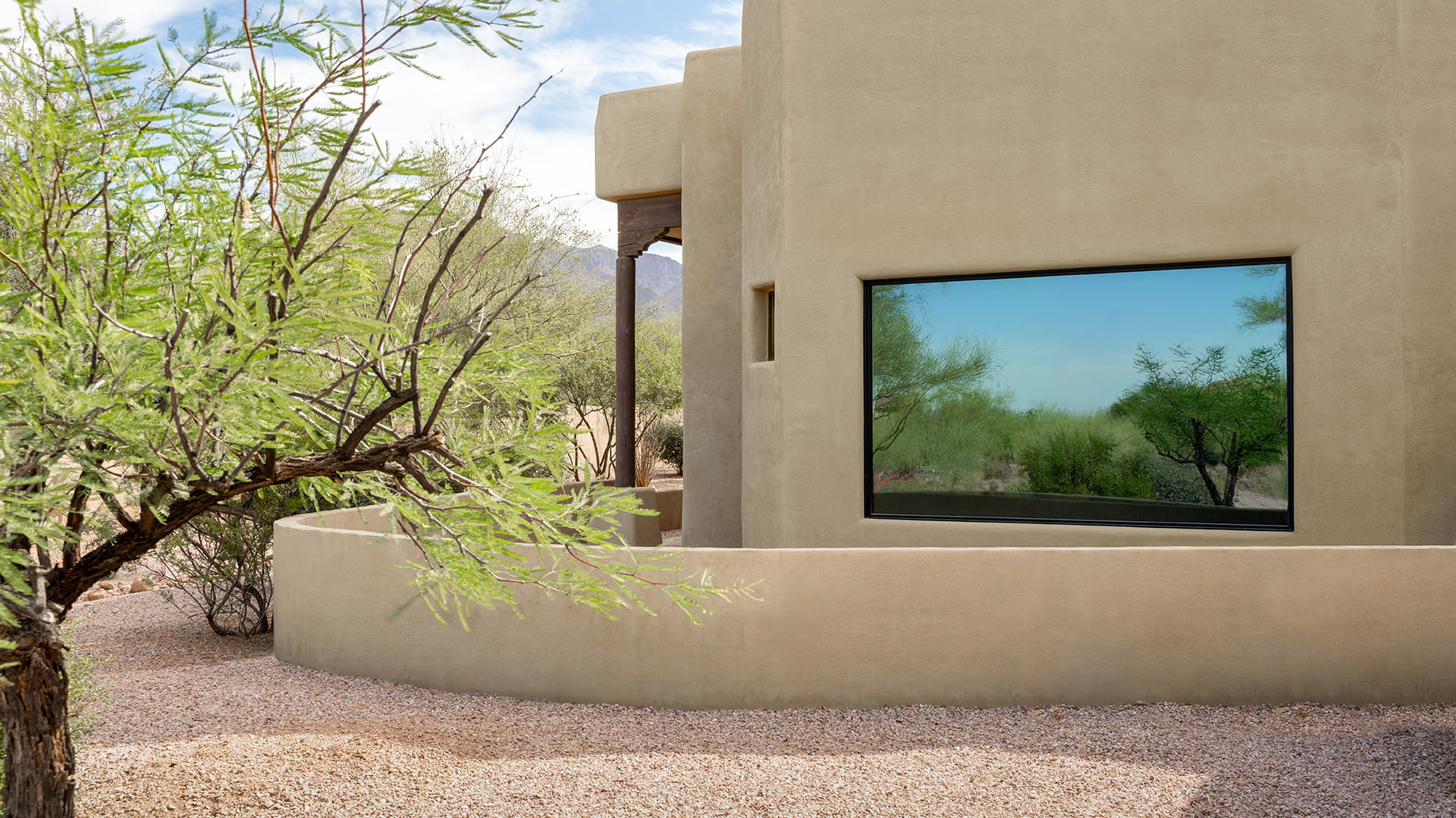 A pueblo-style home exterior with a single large picture window