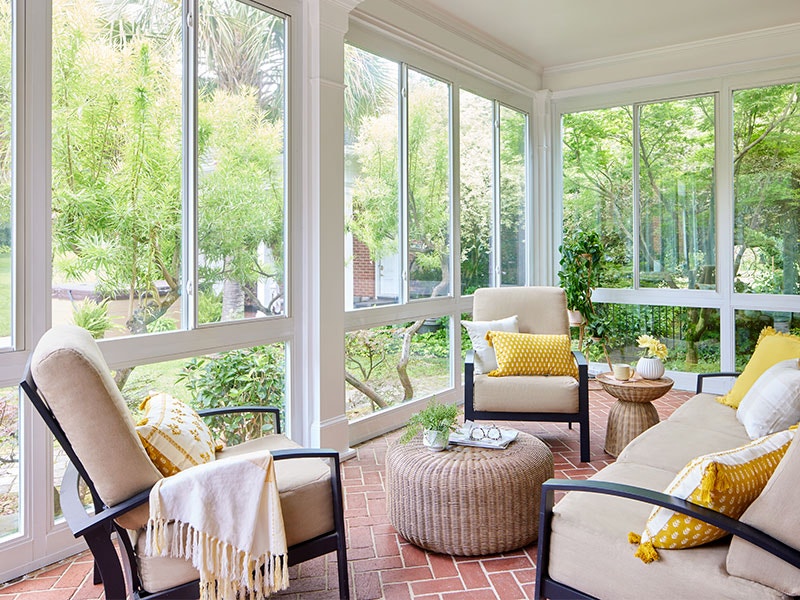 three chairs in a sunroom surrounded by glass sliding windows