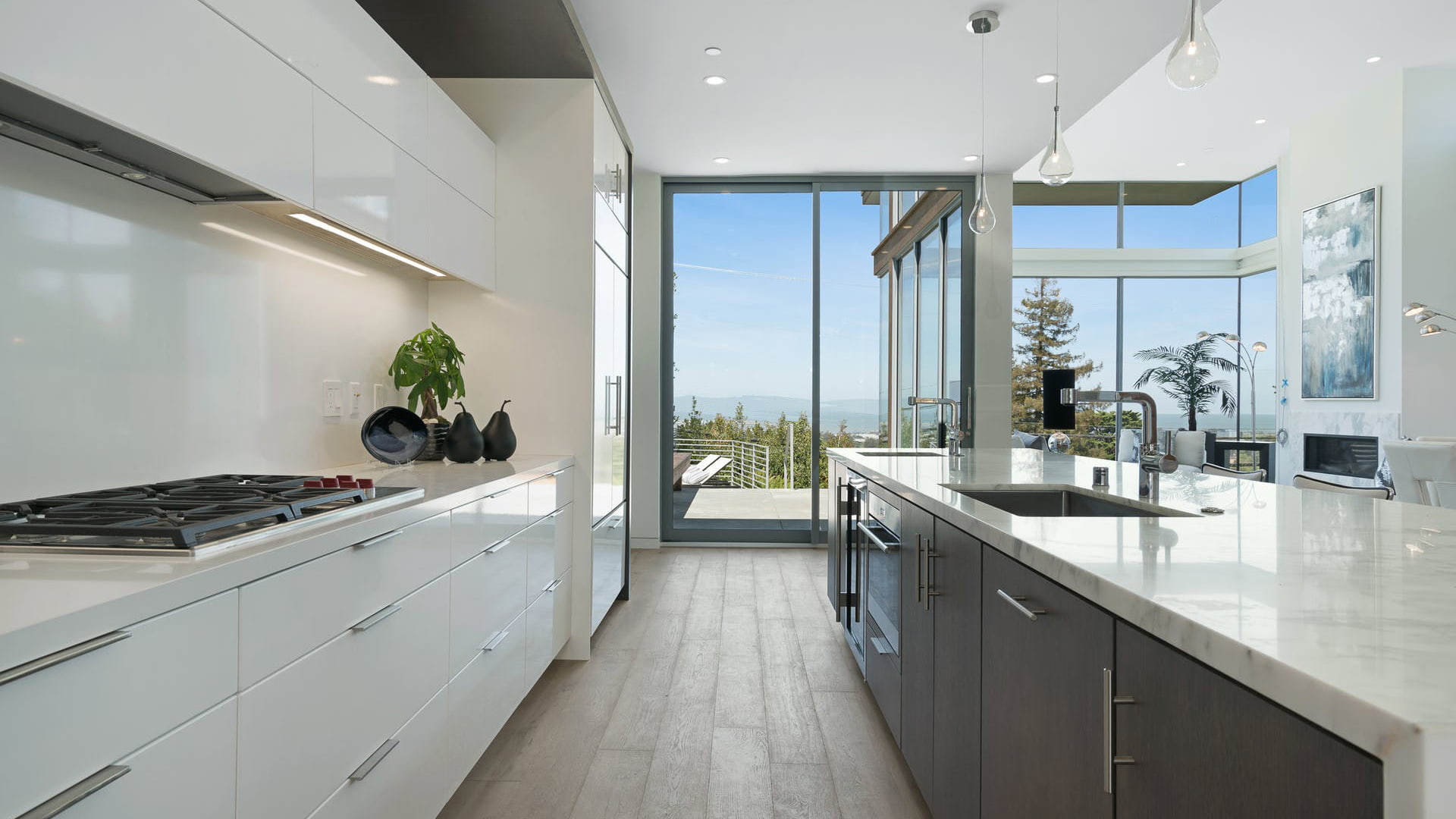 A galley kitchen with modern white cabinets and at the other side a sliding patio door