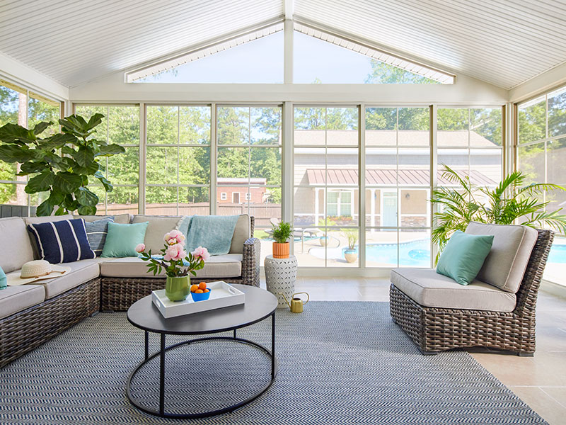 sunroom interior with a wall of vertical sliding windows that lead to a pool