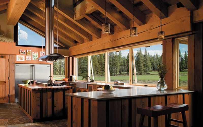 Four wood awning windows are cracked open in an all-wood kitchen with a rustic feel