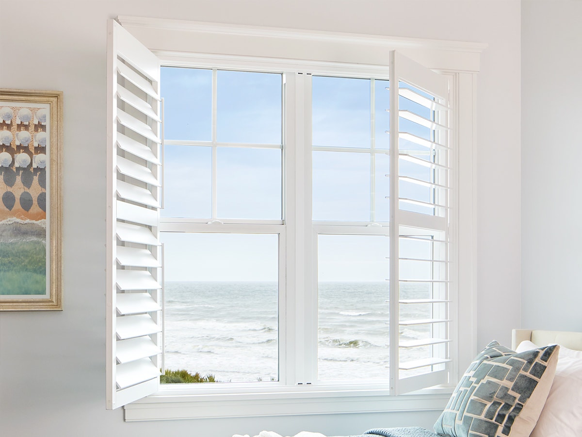 two white shutters on white single-hung windows with an ocean view