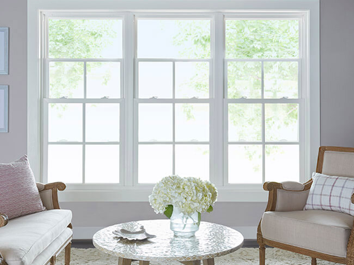 three tall double-hung windows behind a traditional living room arrangement