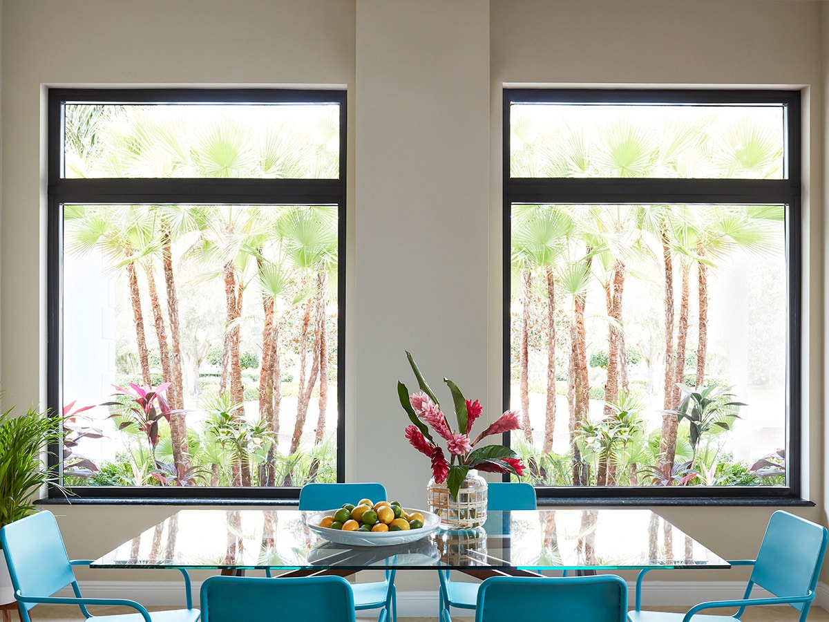 blue chairs around a glass table with two large picture windows behind the table