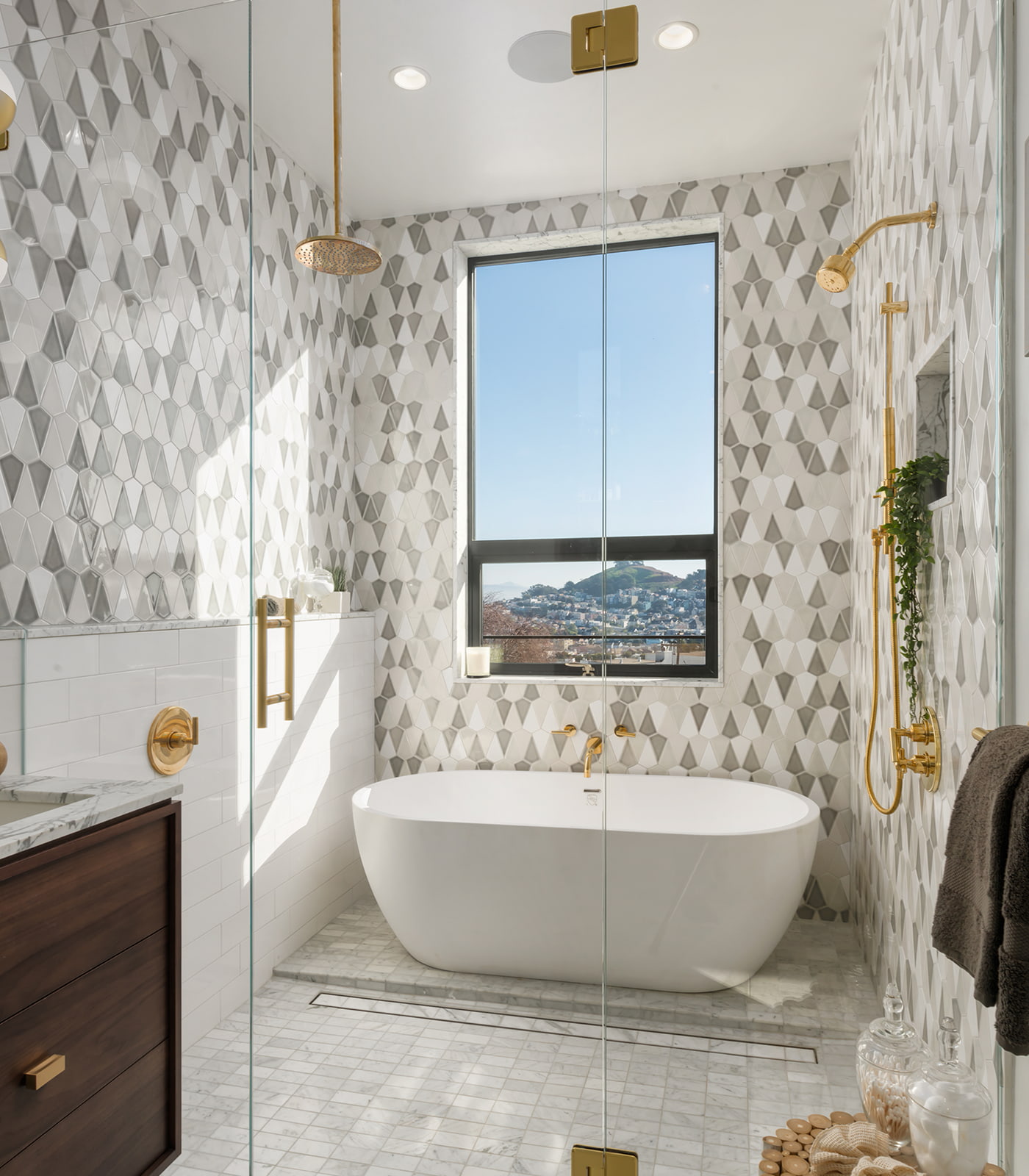 A white soaker tub in a modern bathroom with tri-colored tiles on the wall