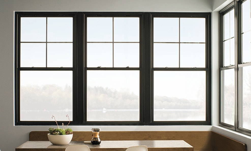 Three black double-hung windows in front of a corner booth kitchen table