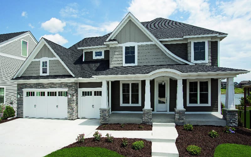 a gray two-story home with white trim and white garage doors